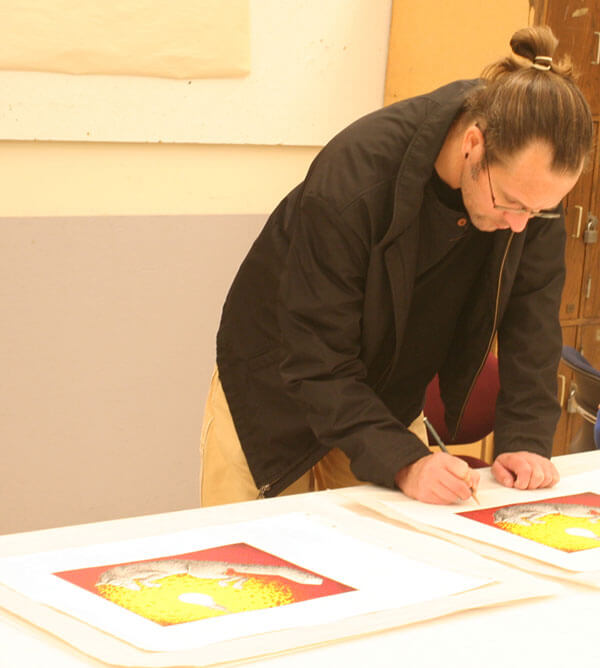 Artist Jason Walker signs his prints at the Normal Editions Workshop.