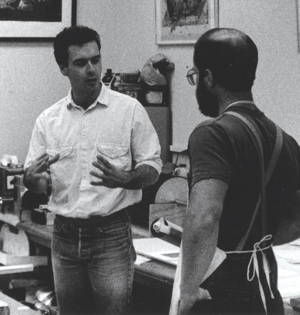 Artist Mark Innerst stands in the studio speaking to fellow Artist Richard Finch.