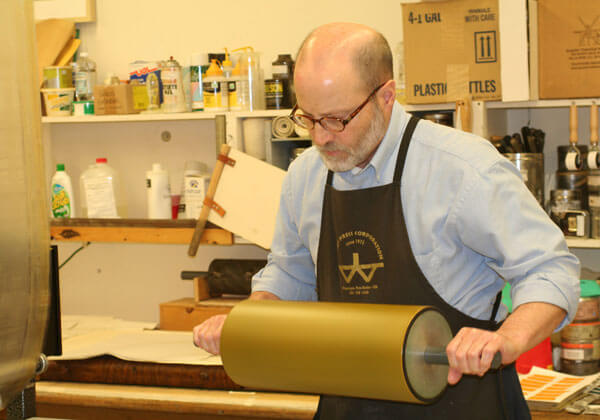Artist Richard Finch uses a print roller in the studio.