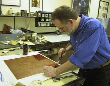 Artist Rod Carswell works with a copper plate in the studio.