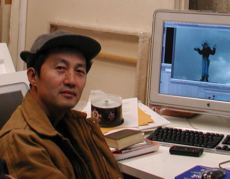 Artist Xiaowen Chen poses at his desk.